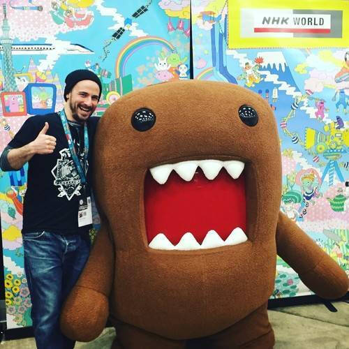 Alumnus Joshua Kahn posing with a "Domo" mascot
